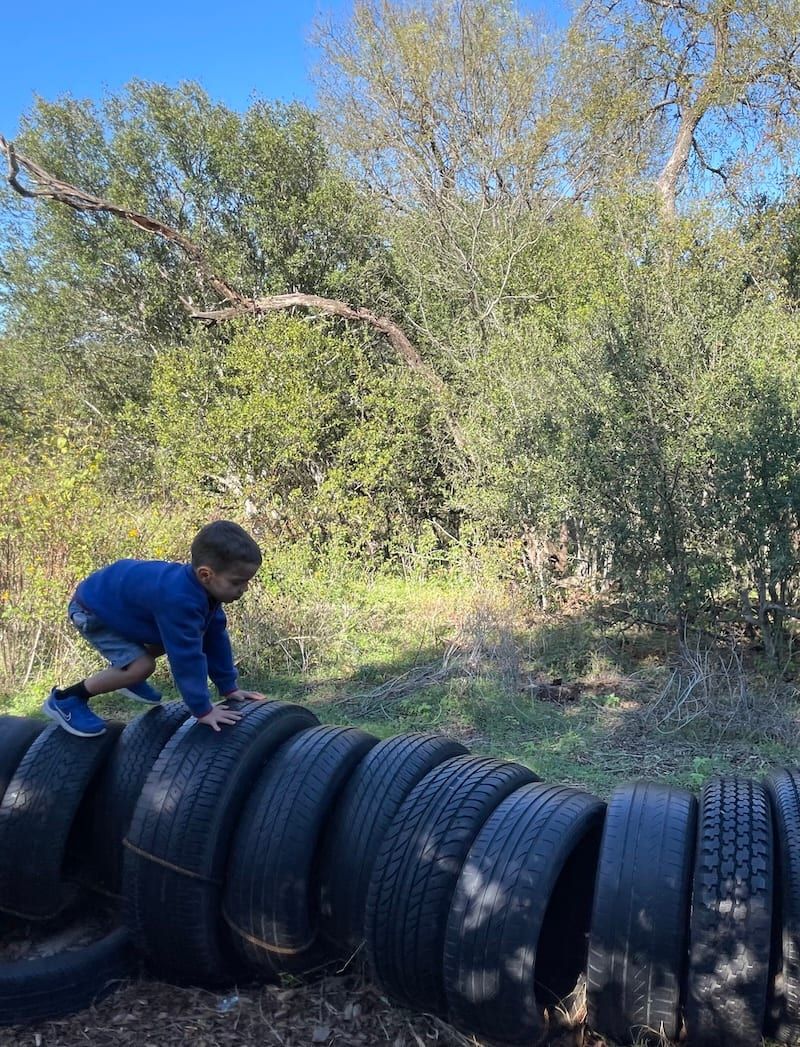 Child climbing on tires in a nature-based therapy setting
